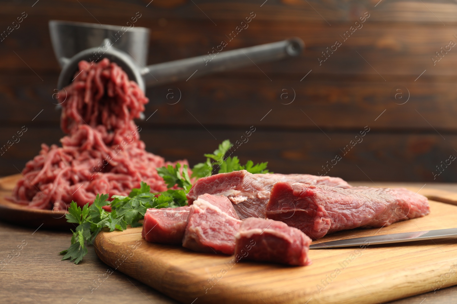 Photo of Manual meat grinder with beef and parsley on wooden table