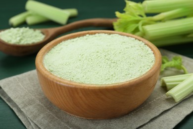 Photo of Natural celery powder and fresh stalks on green table, closeup