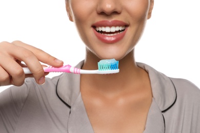 Woman holding toothbrush with paste on white background, closeup