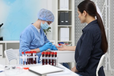 Photo of Laboratory testing. Doctor taking blood sample from patient at white table in hospital