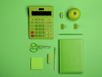 Photo of Flat lay composition with stationery, calculator and apple on green background