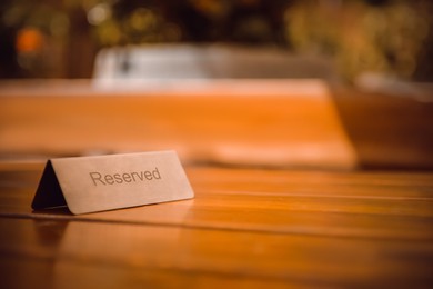 Photo of Sign Reserved on wooden table in restaurant. Space for text