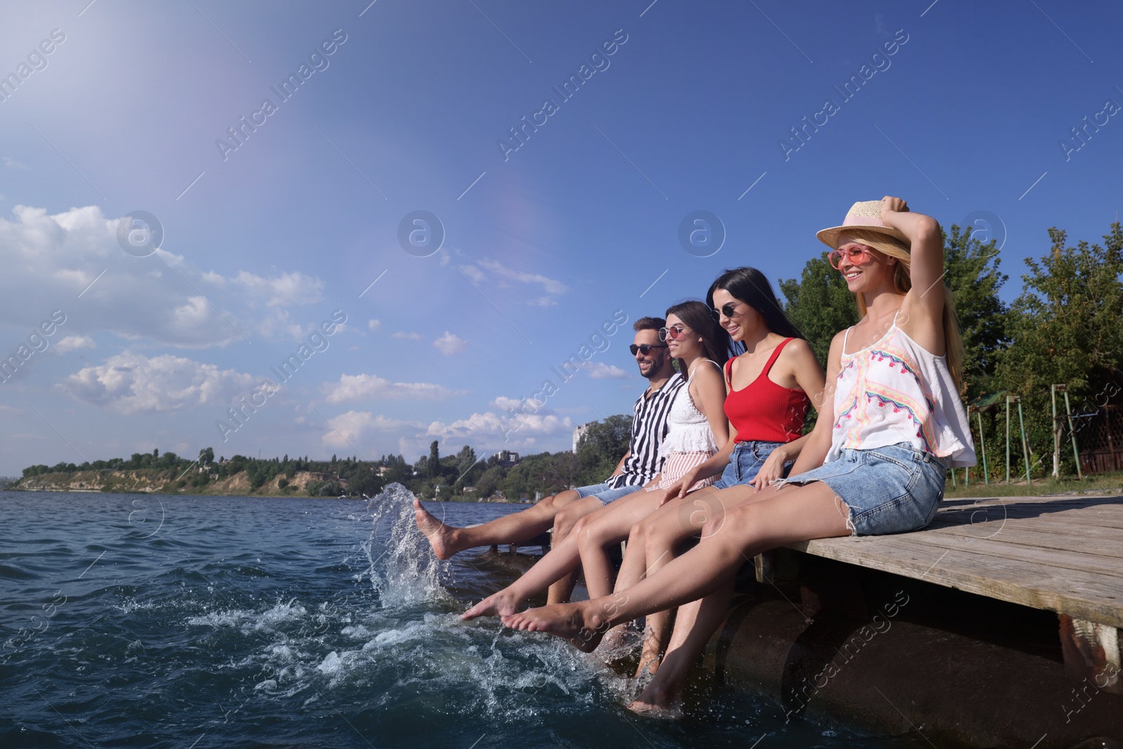 Photo of Group of friends having fun near river at summer party