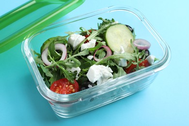 Photo of Tasty salad in glass container on light blue background