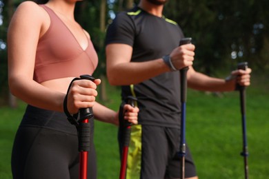 Couple practicing Nordic walking with poles outdoors, selective focus