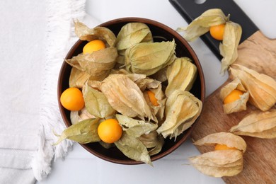Ripe physalis fruits with calyxes on white tiled table, top view