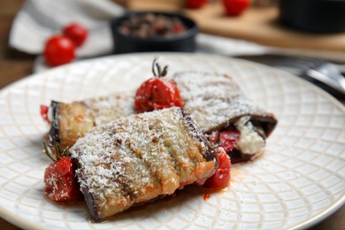 Photo of Delicious baked eggplant rolls with tomatoes and cheese on plate, closeup