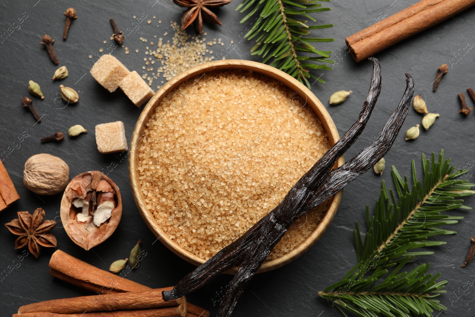 Photo of Different aromatic spices and fir branches on dark textured table, flat lay