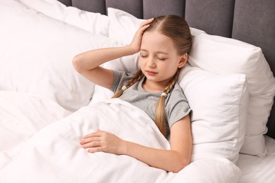 Photo of Little girl suffering from headache in bed