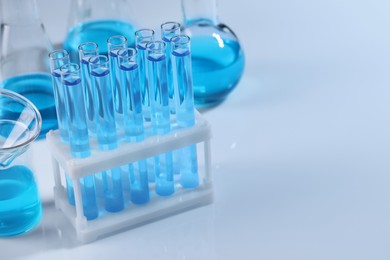 Photo of Laboratory glassware with blue liquid on light background. Space for text