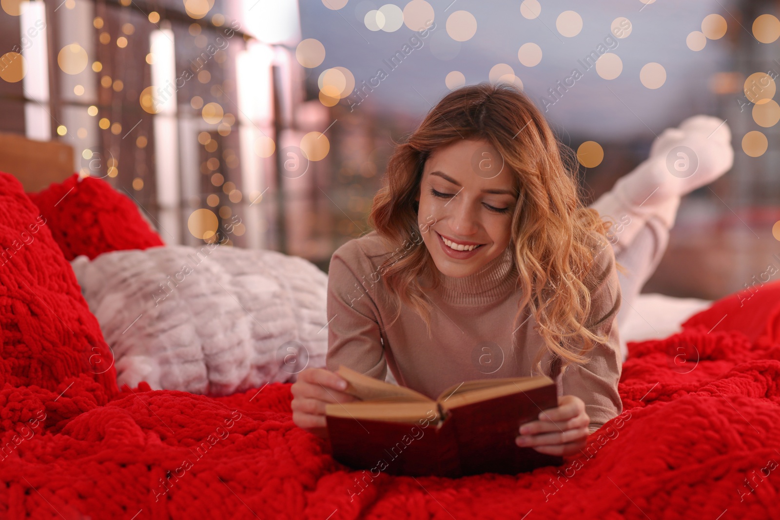 Photo of Beautiful young woman with book relaxing on bed at home. Cozy atmosphere