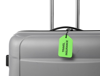 Photo of Grey suitcase with TRAVEL INSURANCE label on white background, closeup