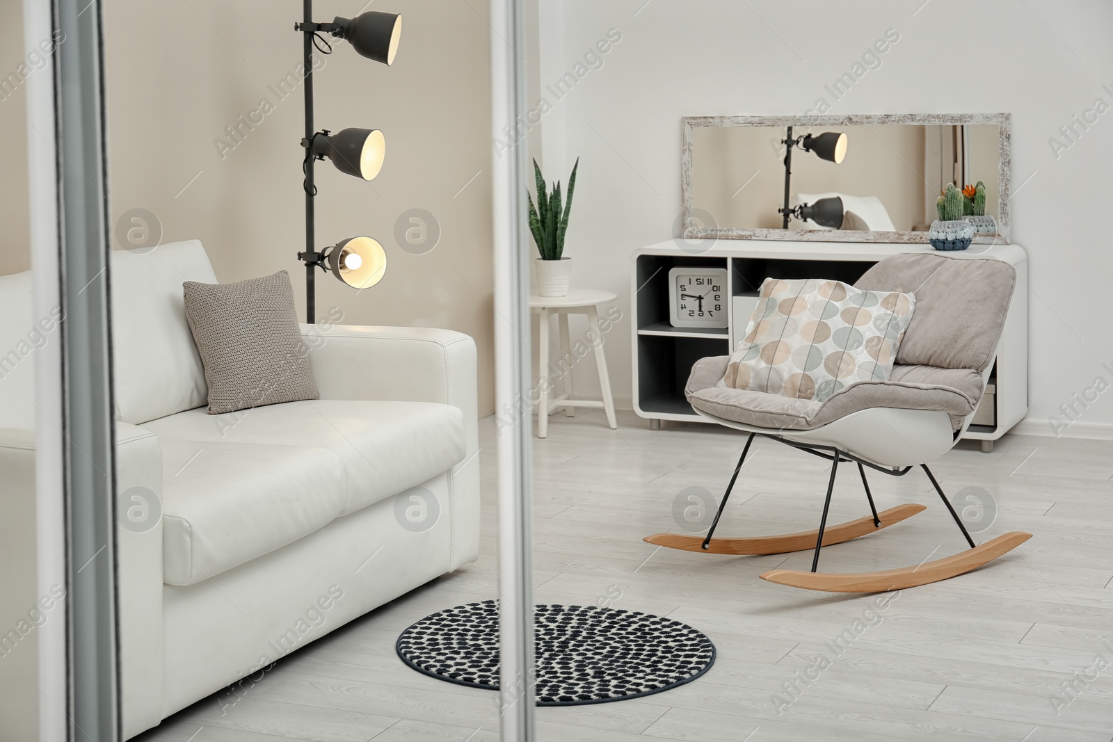 Photo of Beautiful room interior with rocking chair and sofa. Reflection in mirror