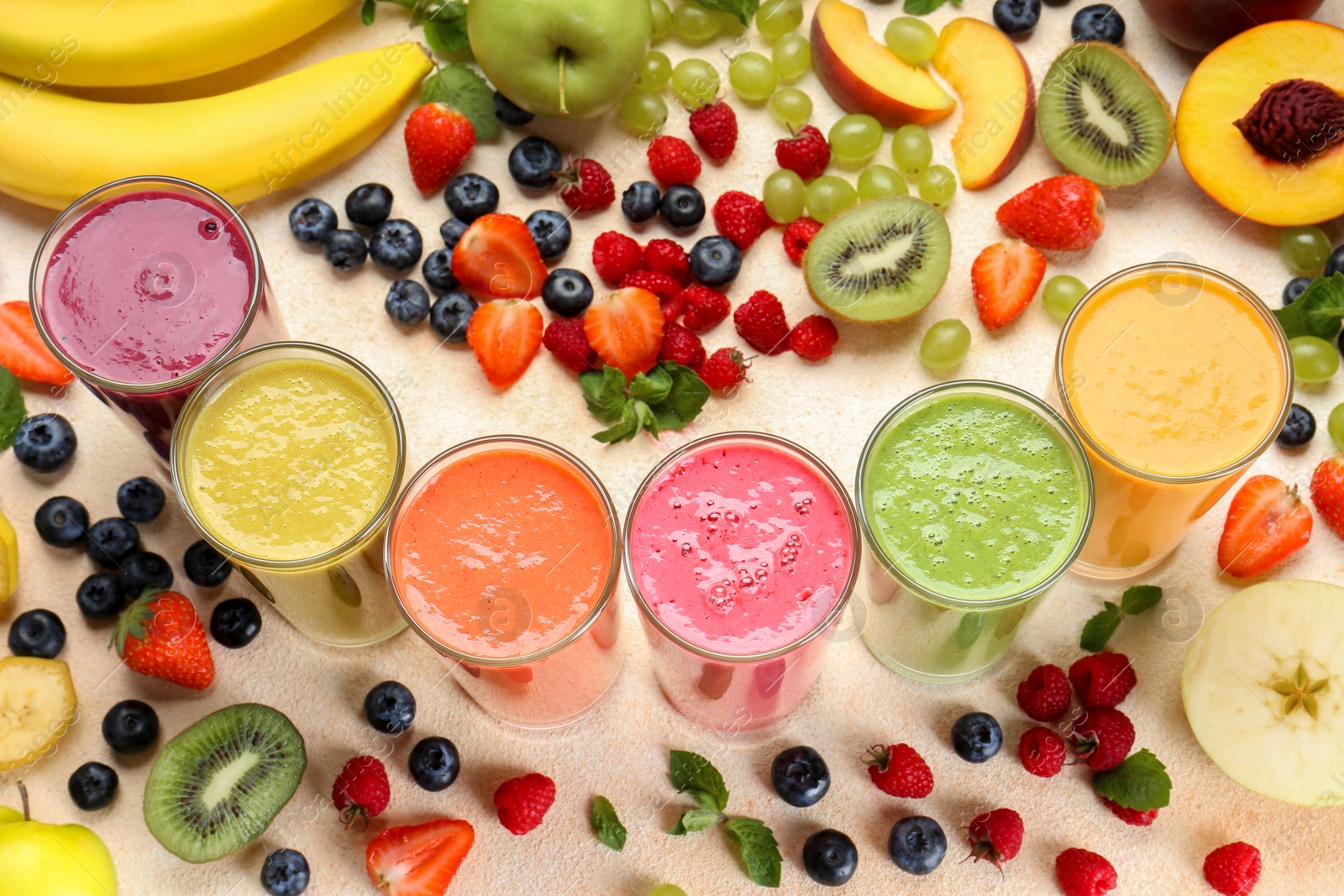 Photo of Composition with fresh colorful fruit smoothies and ingredients on beige table, above view