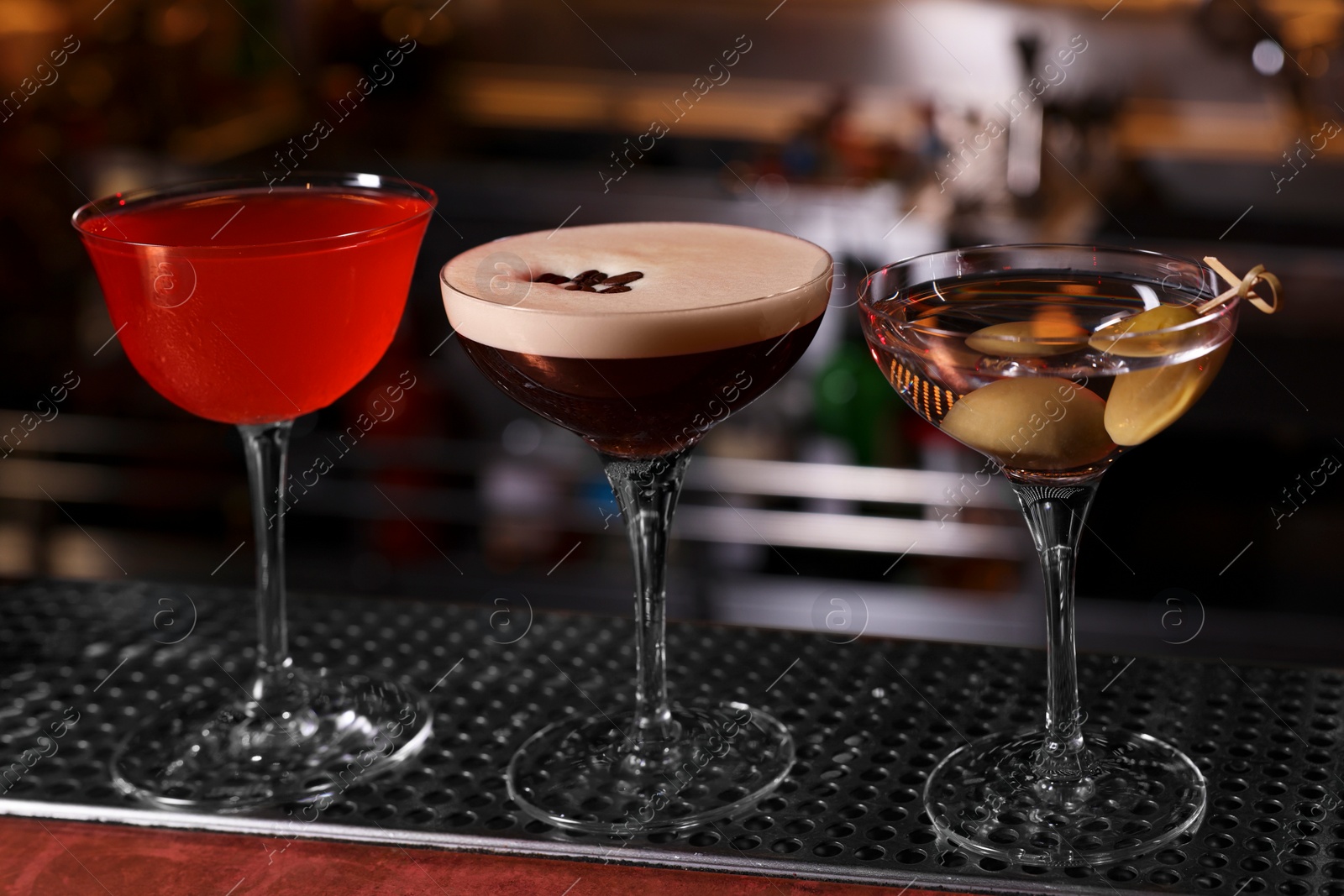 Photo of Glasses of different Martini cocktails on bar counter