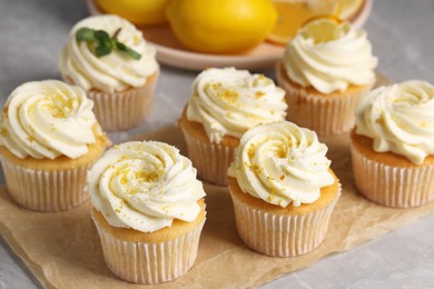 Photo of Delicious cupcakes with white cream and lemon zest on table, closeup