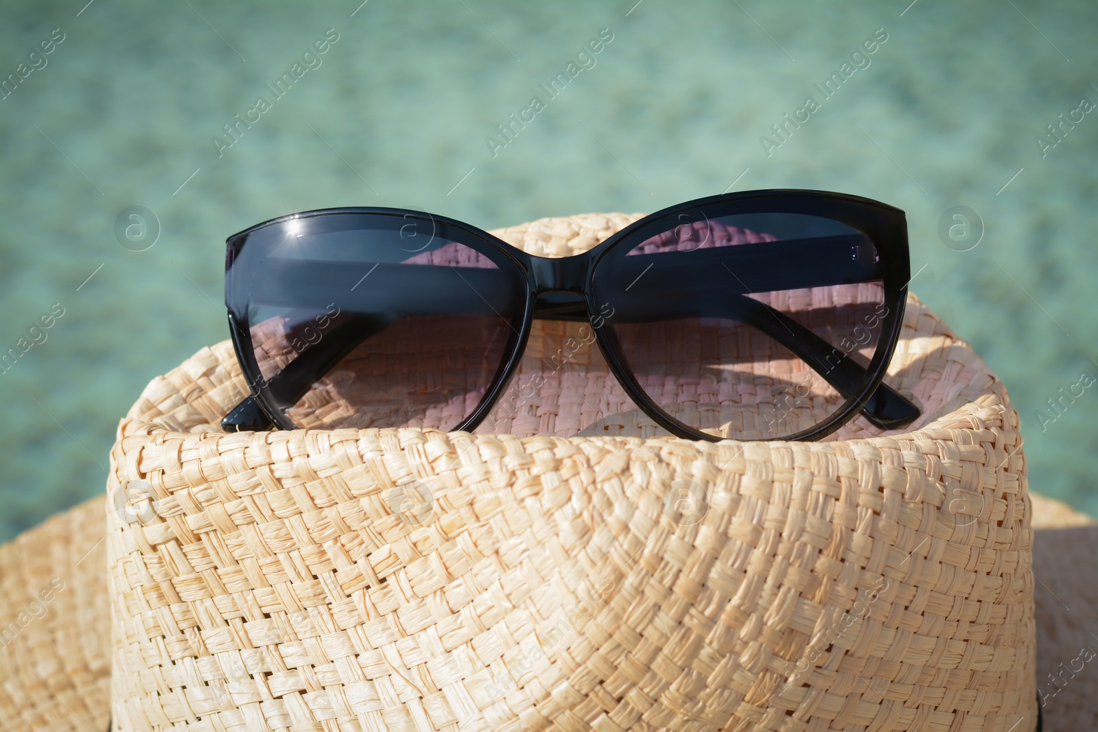 Photo of Stylish hat and sunglasses on blurred background, closeup