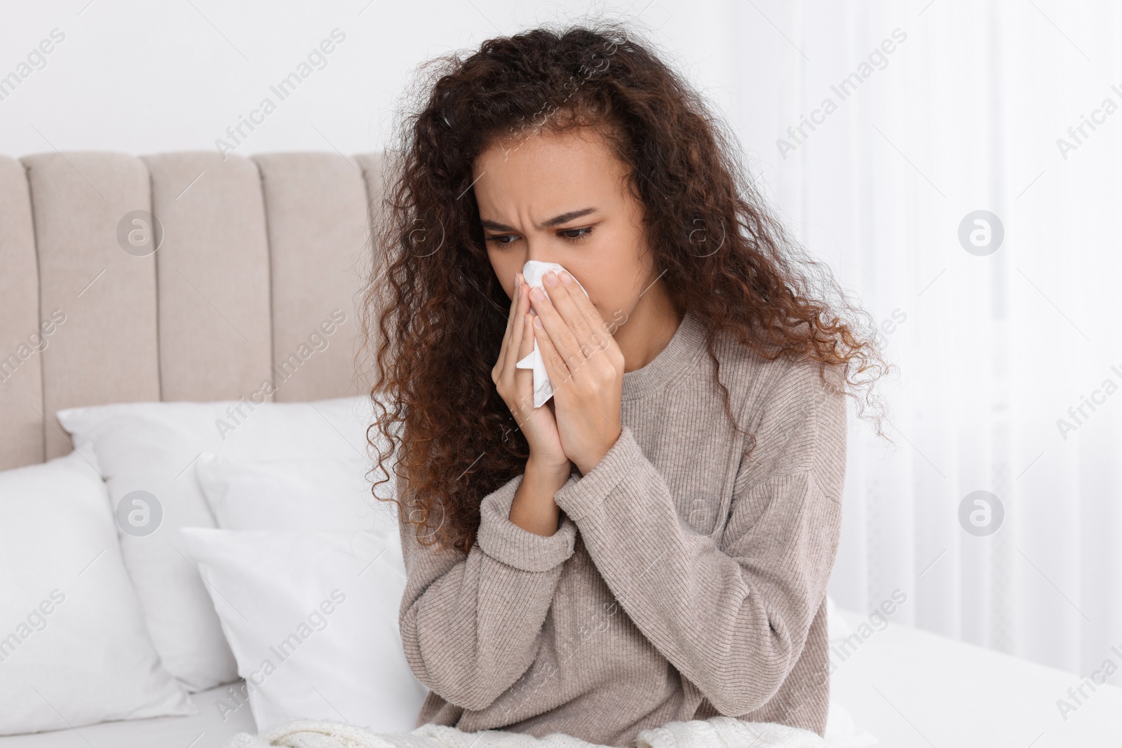 Photo of Sick African American woman with tissue in bed at home