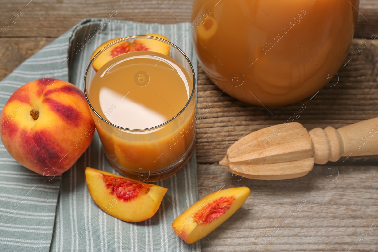 Photo of Delicious peach juice, fresh fruits and citrus reamer on wooden table, above view