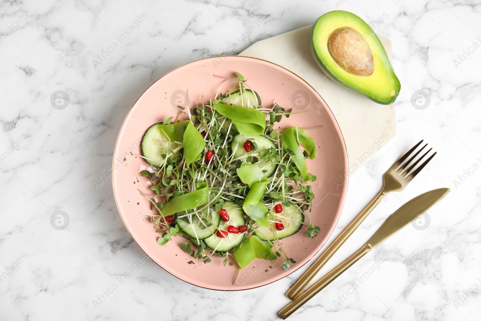 Photo of Salad with fresh organic microgreen in bowl on white marble table, flat lay