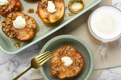 Photo of Tasty baked quinces with nuts and cream cheese served on white marble table, flat lay