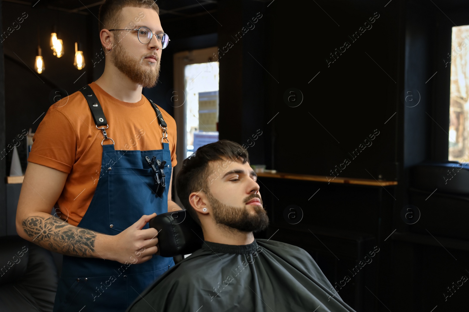 Photo of Professional hairdresser working with bearded client in barbershop