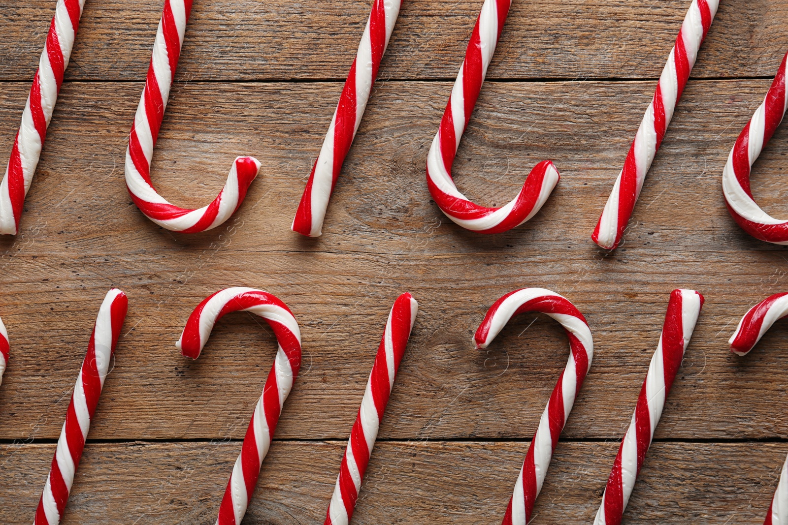 Photo of Flat lay composition with candy canes on wooden background. Traditional Christmas treat