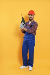 Photo of Young worker in uniform with power drill on yellow background