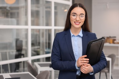 Happy real estate agent with leather portfolio indoors. Space for text