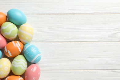 Many colorful painted Easter eggs on wooden background, top view. Space for text