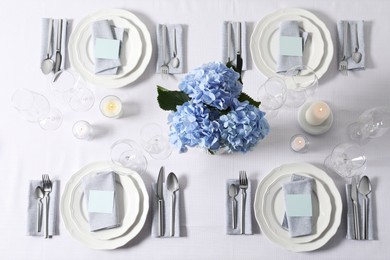 Photo of Beautiful table setting with blank cards, candles and floral decor, flat lay