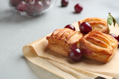 Fresh delicious puff pastry with sweet cherries served on light table