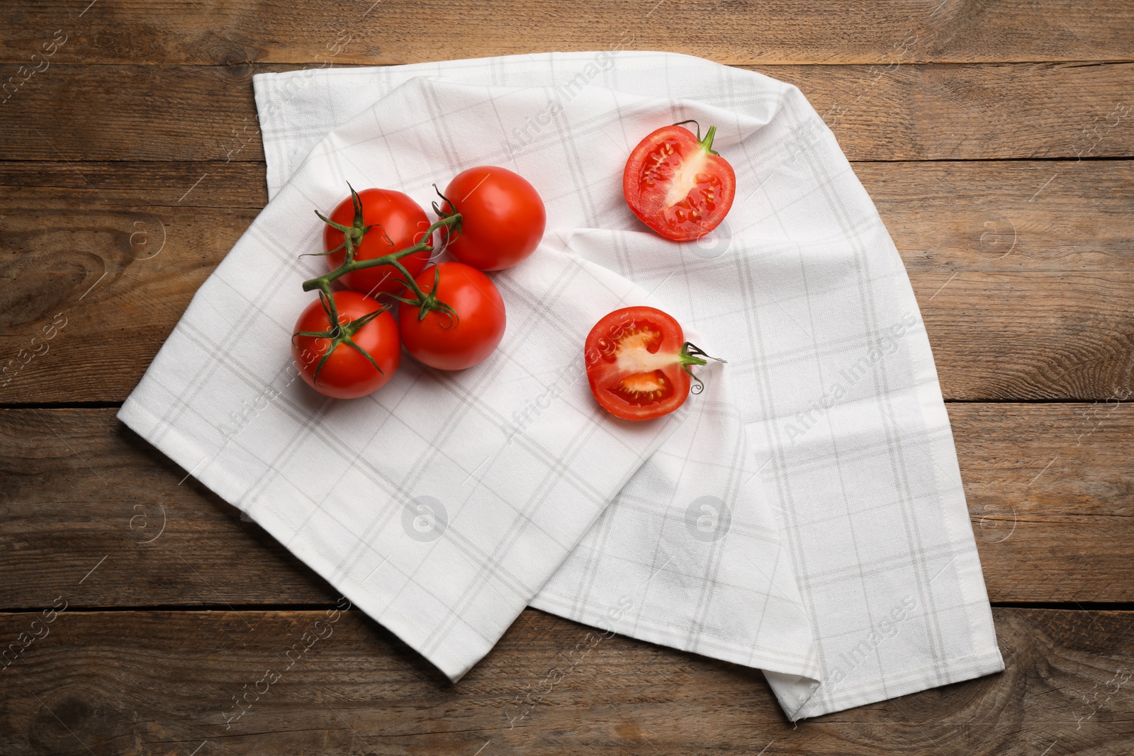 Photo of Kitchen towel and fresh tomatoes on wooden table, flat lay