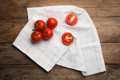 Kitchen towel and fresh tomatoes on wooden table, flat lay