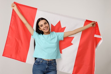 Photo of Happy young woman with flag of Canada on beige background