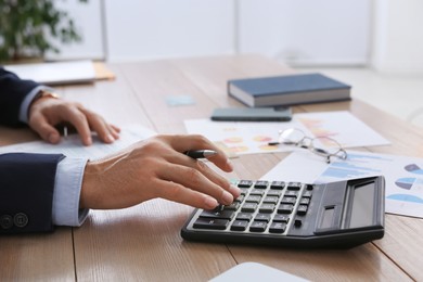Photo of Tax accountant with calculator working at table in office, closeup