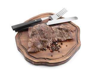 Photo of Piece of delicious grilled beef meat, peppercorns and cutlery isolated on white