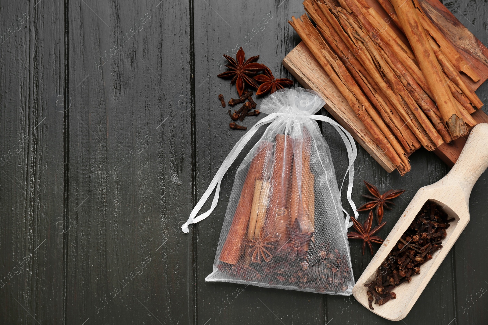 Photo of Scented sachet with cinnamon sticks and anise stars on wooden table, flat lay. Space for text