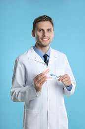 Photo of Dentist with jaws model and toothbrush on light blue background. Oral care demonstration