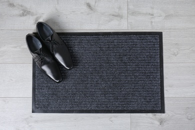 Door mat and shoes on floor, top view. Space for text