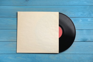 Photo of Vintage vinyl record with paper cover on blue wooden background, top view