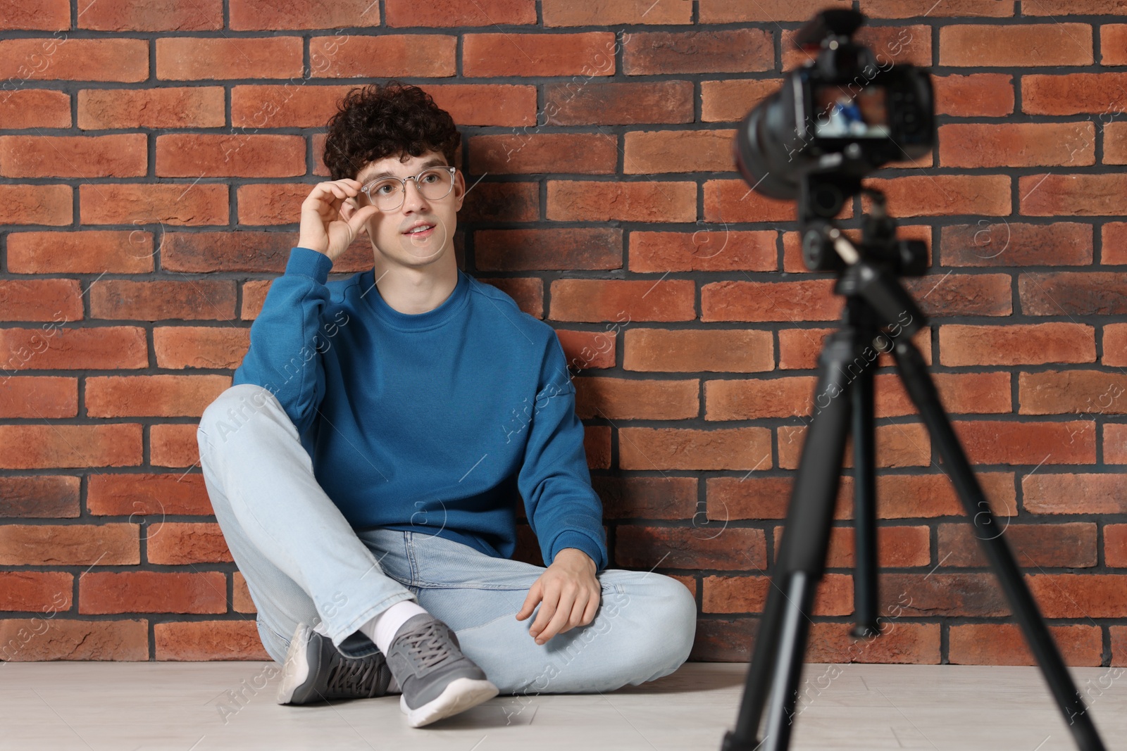 Photo of Teenage blogger in glasses streaming on camera indoors