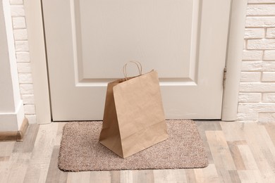 Paper bag on door mat near entrance indoors