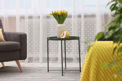 Photo of Spring atmosphere. Stylish living room interior with comfortable furniture and bouquet of beautiful yellow tulips