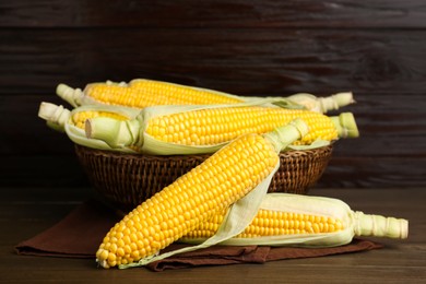 Tasty fresh corn cobs on wooden table