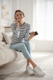 Photo of Young woman listening to music at home
