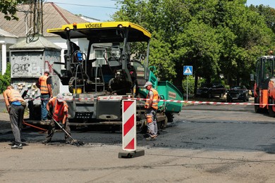 Photo of MYKOLAIV, UKRAINE - AUGUST 04, 2021: Workers with road repair machinery laying new asphalt