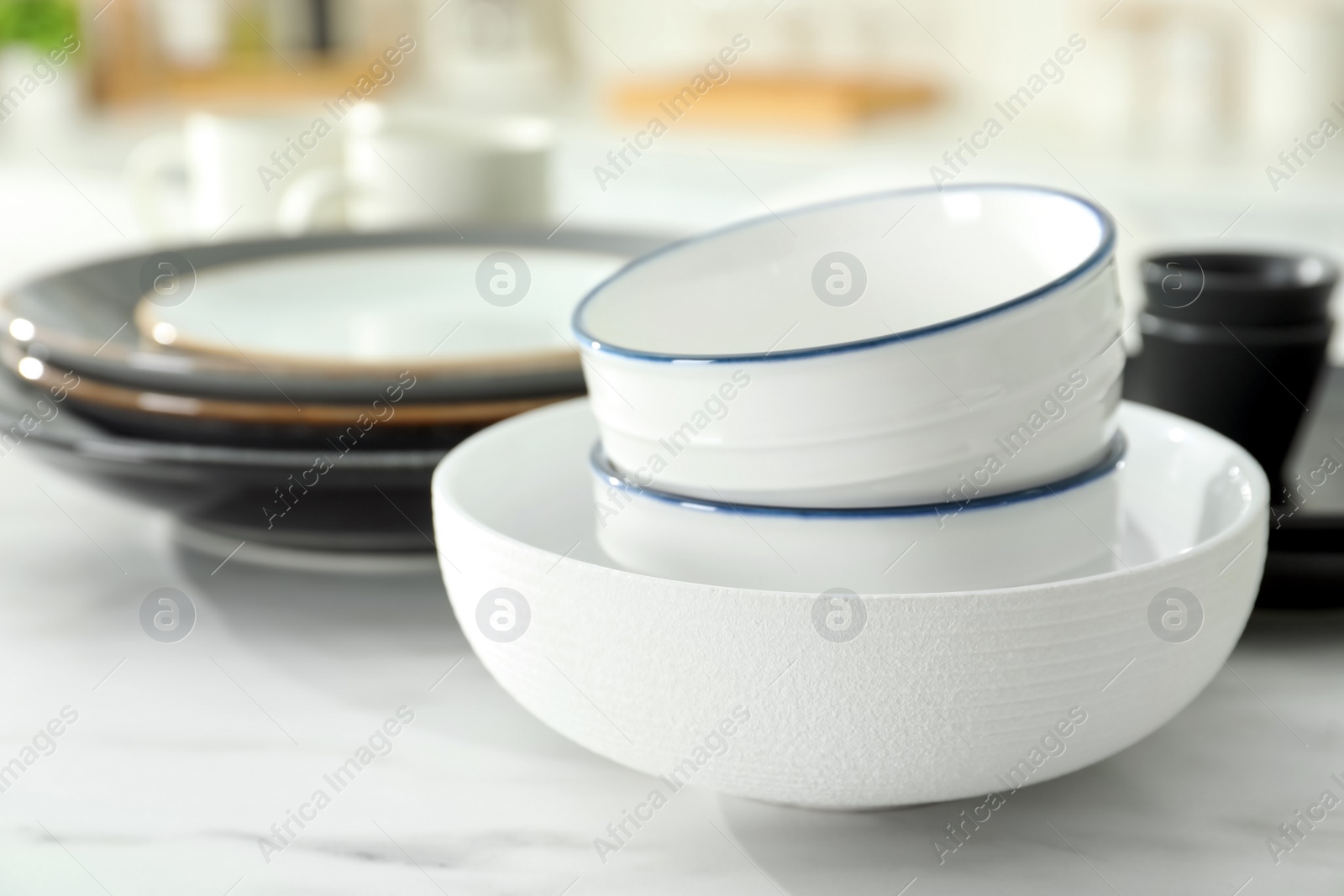 Photo of Set of ceramic tableware on white table in kitchen, closeup