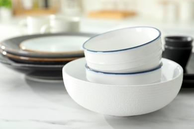 Photo of Set of ceramic tableware on white table in kitchen, closeup