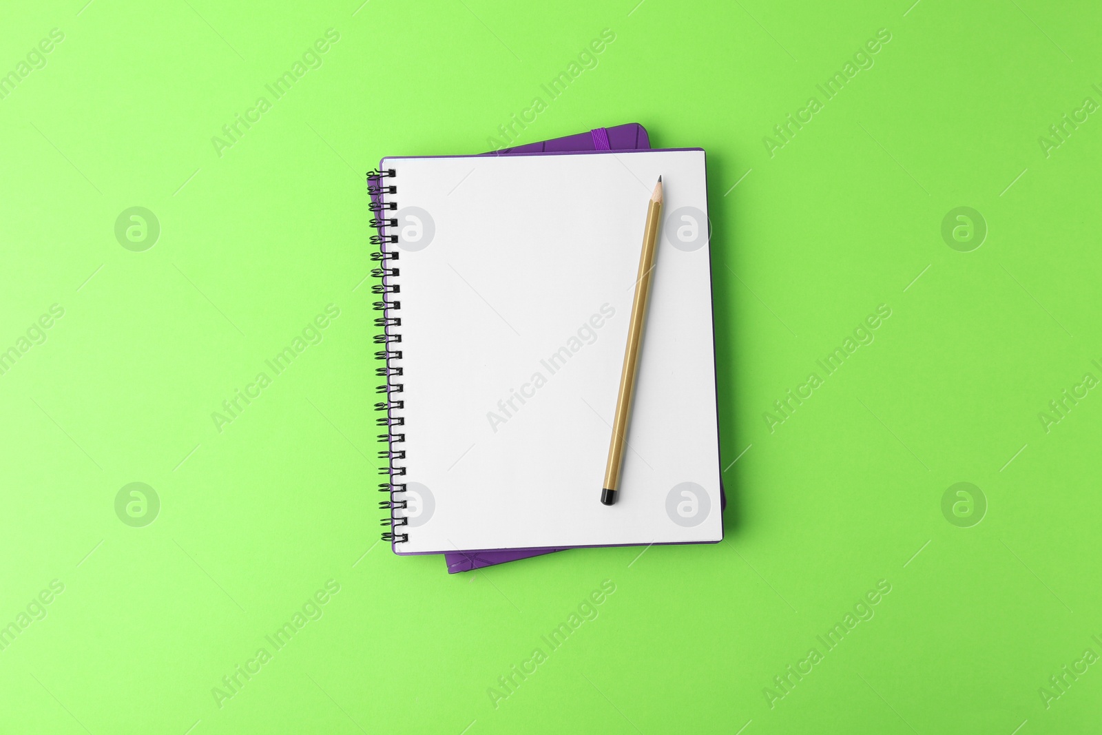 Photo of Notebooks with pencil on light green background, top view